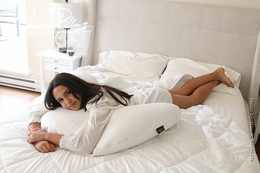 A model lying on a bed, positioned atop a curved pillow. The image is used in a blog post debunking eight common sleep myths.